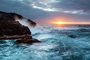 Breaker: Surf, rocky coast with foaming waves at sunset
