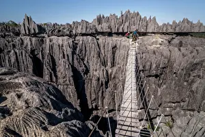 Suspension: Tourist on suspension bridge over gorge in rugged