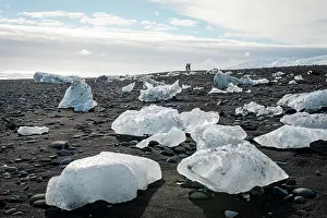 Tourists: Two tourists walking at horizon, ice floes on black