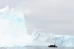 Calving: Tourists on a Zodiac cruising amongst massive Icebergs