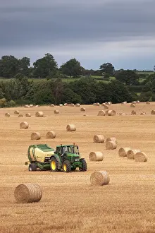 Tractors: Tractor making bales of hay in freshly cut wheat