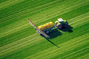 Manuring: Tractor with pesticide sprayer on meadow, fertilizing