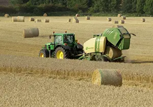 Pulling: Tractor pulling straw baling machine in field
