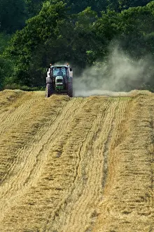 Pulling: Tractor pulling straw baling machine in field