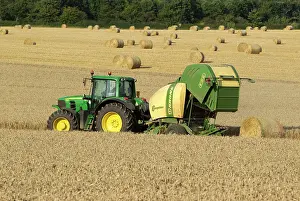 Pulling: Tractor pulling straw baling machine in field
