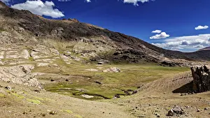 Clear: Vast, mountainous landscape under a clear blue sky with white clouds