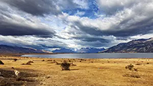 Quiet: A vast, peaceful landscape with a calm lake and mountains under dramatic clouds