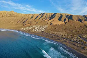 Playa: View on beach Playa Famara with bungalows and mountain