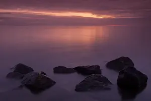 Dyke: View over lake during sunrise with stones in foreground