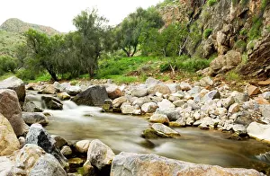 Strewn: Water flows through a rock strewn valley in the