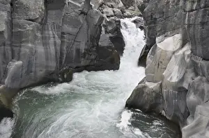 Waterfalls: A waterfall cascading through gray rocky canyons amidst rugged terrain