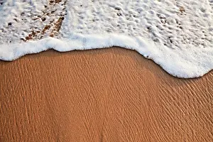 Spray: Wave surging on sand on beach