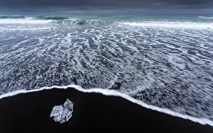 Cubes: Waves rolling over the ice cubes on the black lava beach