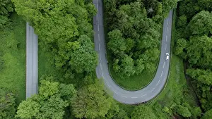 Driving: White car driving on serpentine road through green