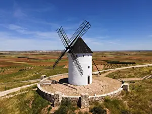 Wind: White windmill with black roof on a hill surrounded