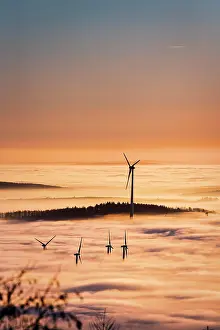 Economy: Wind turbines and forest rising from cloud cover