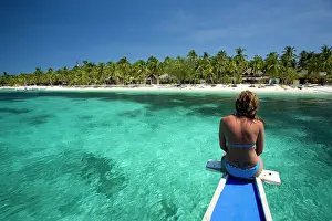 Visayan: woman on boat looking the beach with palm trees, Malapascua