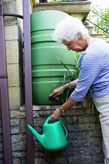 Butt: Woman filling watering can from rainwater butt