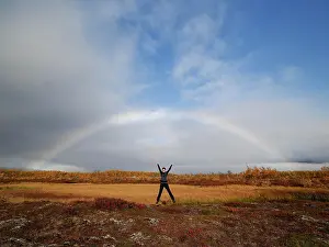 Norrbotten: Woman is jumping in the air under rainbow, autumn