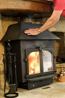 Evironment: Woman - keeping warm warming hands on woodstove