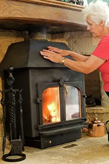 Evironment: Woman - keeping warm warming hands on woodstove