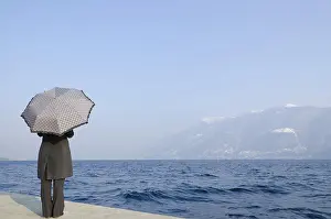 Forecast: Woman Standing on the Waterfront with an Umbrell
