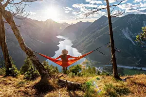 Comfortable: Woman with a sun hat sitting in an orange hammock
