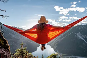 Comfortable: Woman with a sun hat sitting in an orange hammock
