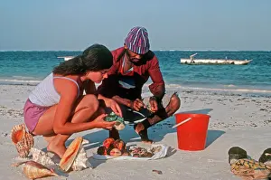 Selling: Woman tourist buying exotic shells from beach trader