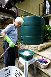 Butt: Woman using rainwater from large outside storage
