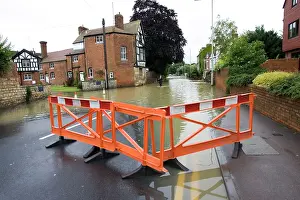 Tewkesbury: Woman walking along flooded road into Tewkesbury near Abbey