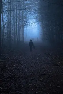Monochrome: Woman walking through the forest at dusk towards three other