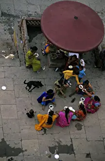 Uttar: Women eating in the street and dog Varanaci India