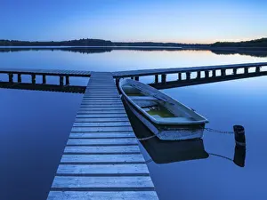 Boats: Wooden jetty with rowing boat at dusk, after sunset on Lake