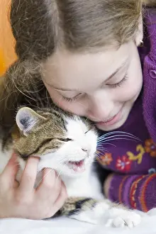 Enjoyment: Ten year old girl hugging her cat