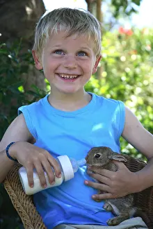 Smiles: Young boy giving the bottle a rabbit France
