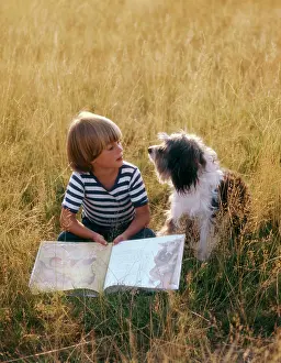 Reading: Young boy reading with his dog, a Bearded Collie