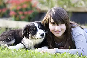 Ager: Young Girl and Australian Shepherd pupy lying in grass