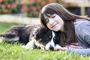 Ager: Young Girl and Australian Shepherd pupy lying in grass