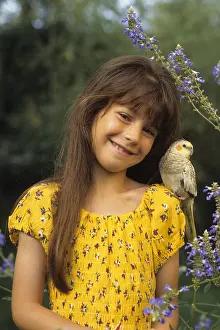 Smiles: Young girl carrying a Cockatiel on her shoulder