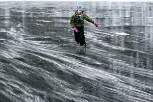 Skating: Young Girl ice skating on the smooth ice of a frozen