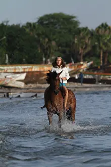 Halter: Young girl riding bareback in the sea - Senegal