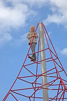 Playgrounds: Young girl smiling at top of space climbing net