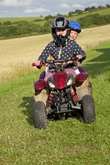 Bikes: Young girls riding mall quad bike - in farm field