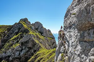 Cable: Young man climbing a rock face, via ferrata to the