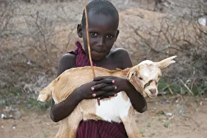 Peoples: Young Masai shepherd carrying a goat Tanzania