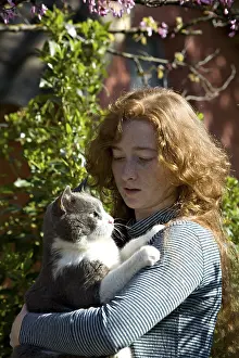 Cherished: Young red-haired girl carying a cat in a garden