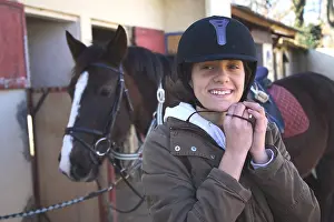 Smiles: Young rider putting her bomb before getting on Horseback