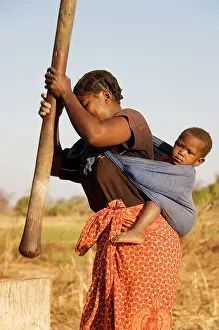 Pounding: Zambia - Tonga woman with child on her back pounding