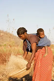 Mothes: Zambia - Tonga woman with child sifts grains near